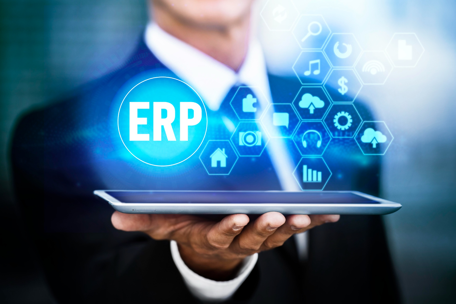 A person in a suit holds a tablet that displays a glowing "ERP" icon